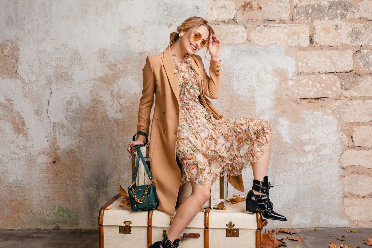 attractive-stylish-blonde-woman-beige-coat-sitting-suitcases against-wall street